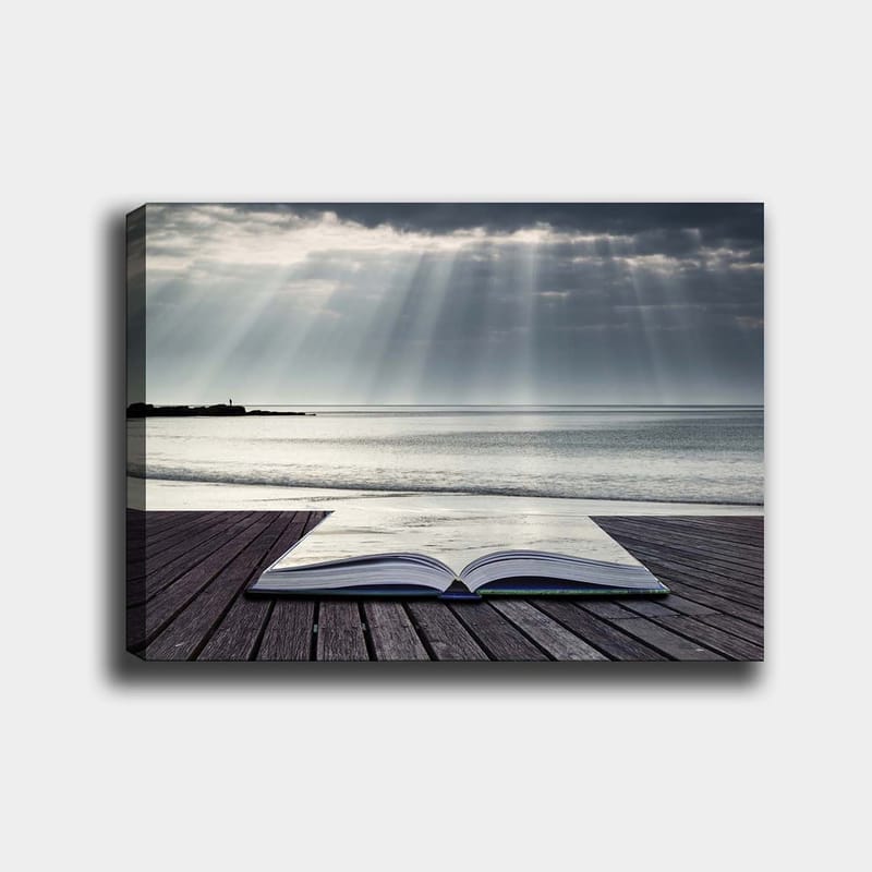 Lærred 70x100 cm - Åben bog liggende på en træmole ved havet, omgivet af bløde lysstråler fra en overskyet himmel, Grå / Blå / Hvid