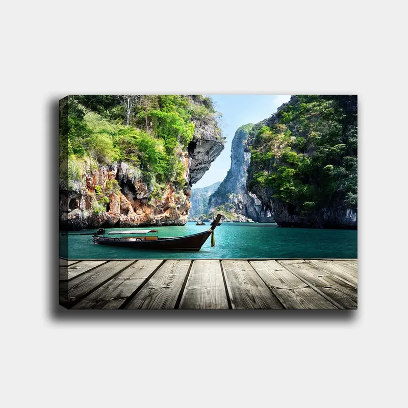 Lærred 70x100 cm - Båden ligger stille på en klippefyldt kyst omgivet af frodige bjerge og klart vand, Grøn / Blå / Brun