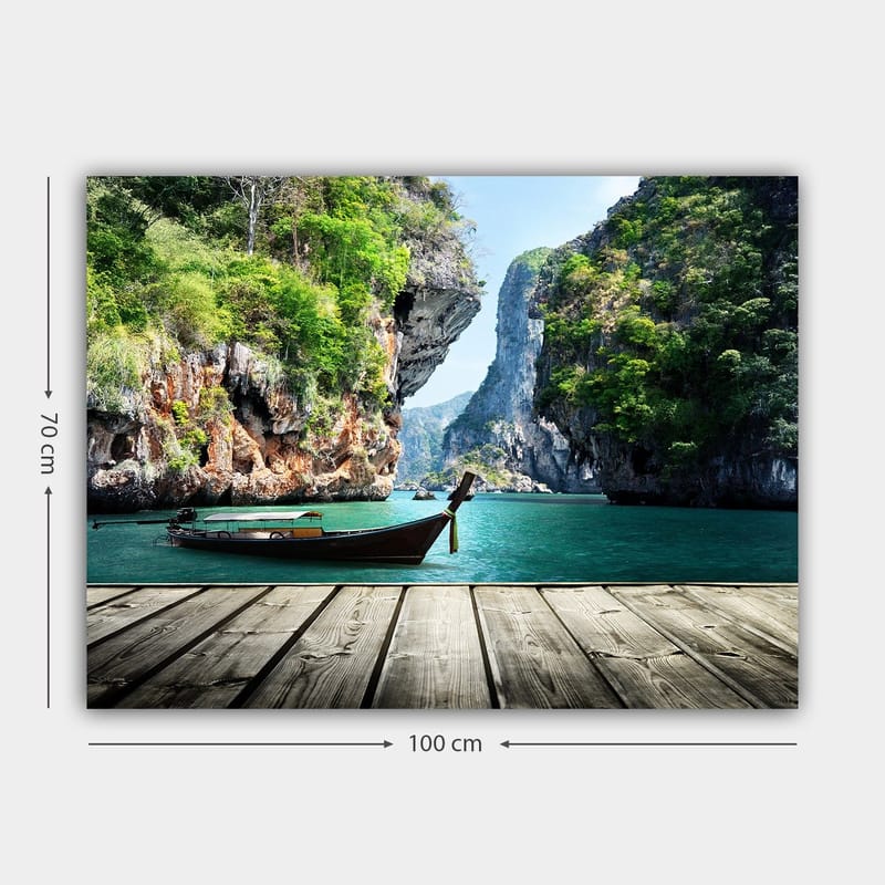 Lærred 70x100 cm - Båden ligger stille på en klippefyldt kyst omgivet af frodige bjerge og klart vand - Grøn / Blå / Brun - Boligtilbehør - Billeder & kunst - Billeder på lærred