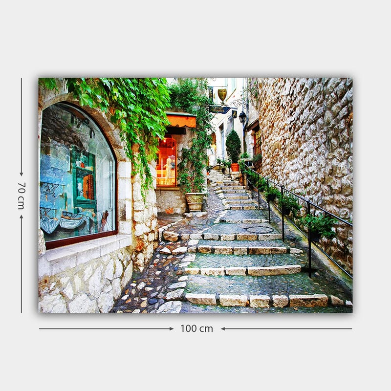 Lærred 70x100 cm - Charmerende gyde med sten og grønne områder, der fører opad, omgivet af historiske bygninger - Grøn / Beige / Orange - Boligtilbehør - Billeder & kunst - Billeder på lærred