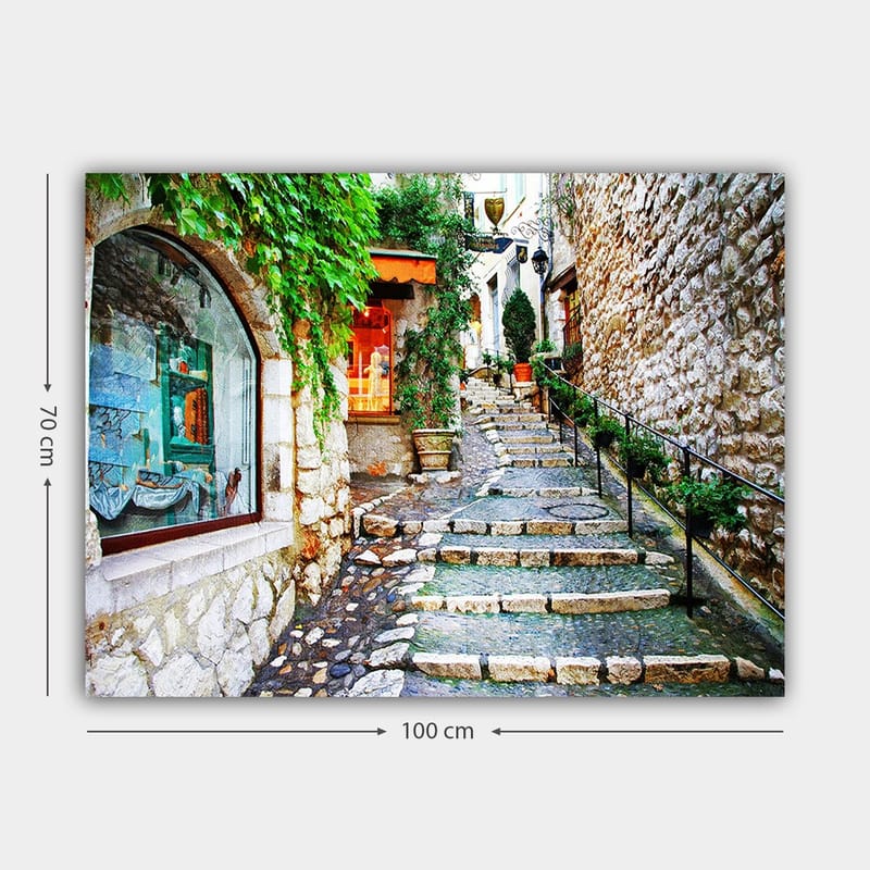 Lærred 70x100 cm - Charmerende gyde med sten og grønne områder, der fører opad, omgivet af historiske bygninger - Grøn / Beige / Orange - Boligtilbehør - Billeder & kunst - Billeder på lærred