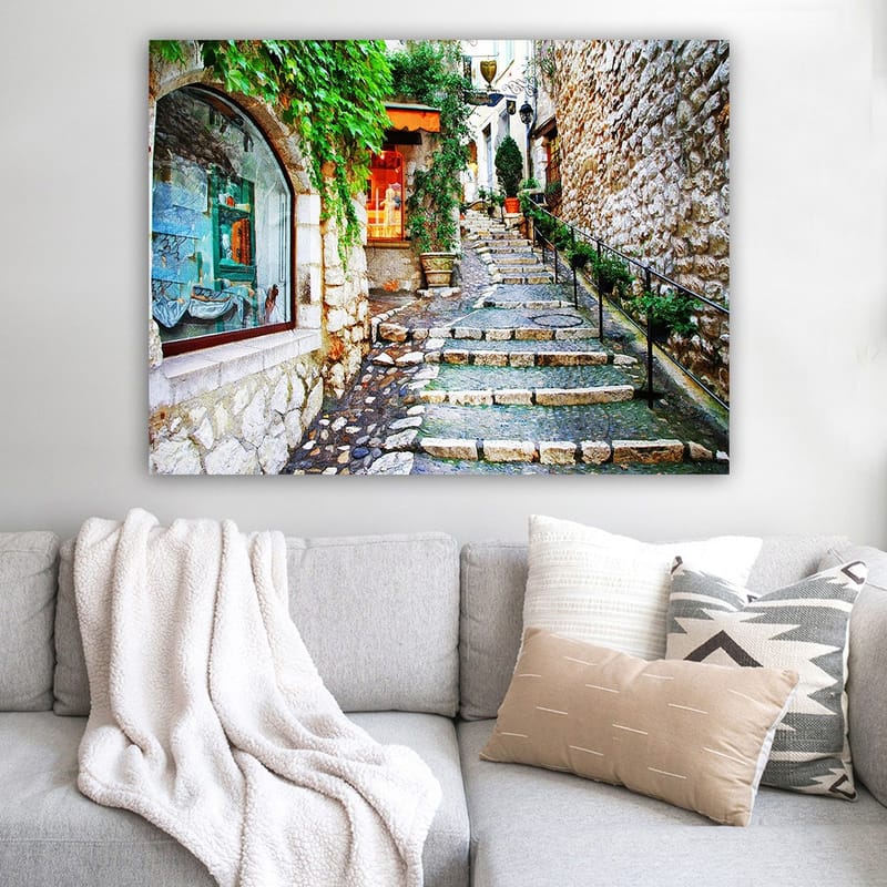 Lærred 70x100 cm - Charmerende gyde med sten og grønne områder, der fører opad, omgivet af historiske bygninger - Grøn / Beige / Orange - Boligtilbehør - Billeder & kunst - Billeder på lærred