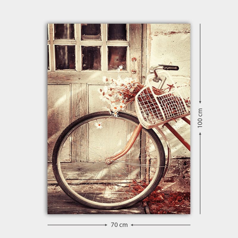 Lærred 70x100 cm - Cykel med en kurv fyldt med blomster foran en gammel dør - Grå / Brun / Hvid - Boligtilbehør - Billeder & kunst - Billeder på lærred