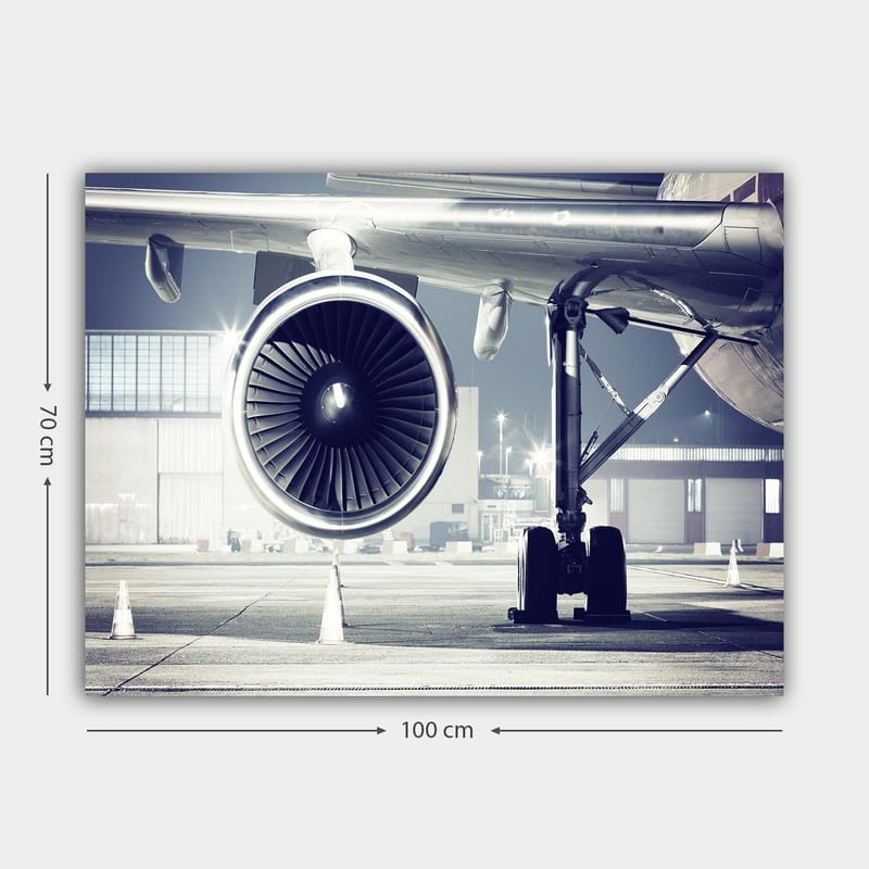 Lærred 70x100 cm - Detaljeret visning af en flymotor og dens understel i en lufthavn - Grå / Sort / Sølv - Boligtilbehør - Billeder & kunst - Billeder på lærred