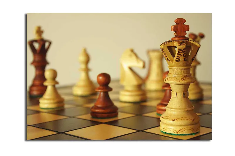 Lærred 70x100 cm - Et skakbræt med træbrikker i fokus, hvor dronningen står prominent, Lysebrun / Mørkebrun / Beige