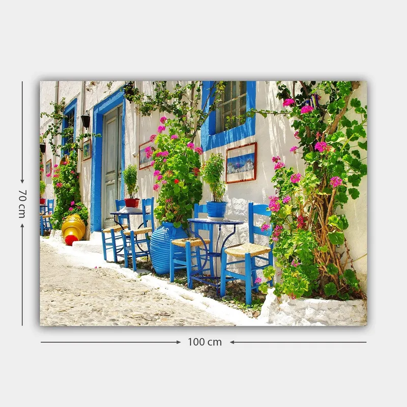 Lærred 70x100 cm - Farverig og livlig gade med blå stole og blomsterkrukker i middelhavsmiljø - Blå / Grøn / Lyserød - Boligtilbehør - Billeder & kunst - Billeder på lærred