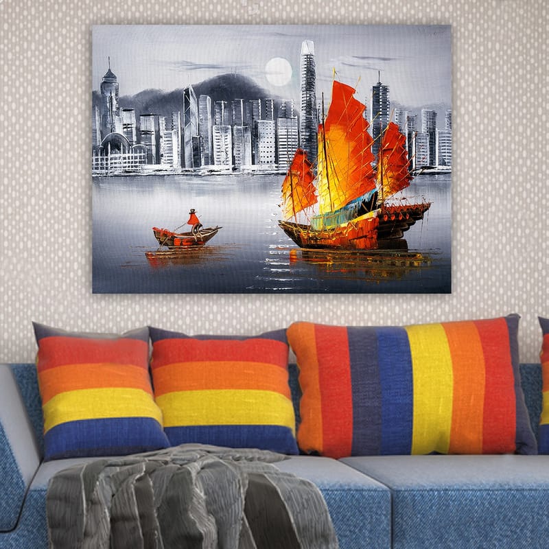 Lærred 70x100 cm - Farverig sejlbåd med røde sejl på en spejlblank vandoverflade, omgivet af et moderne bybillede - Rød / Orange / Blå - Boligtilbehør - Billeder & kunst - Billeder på lærred