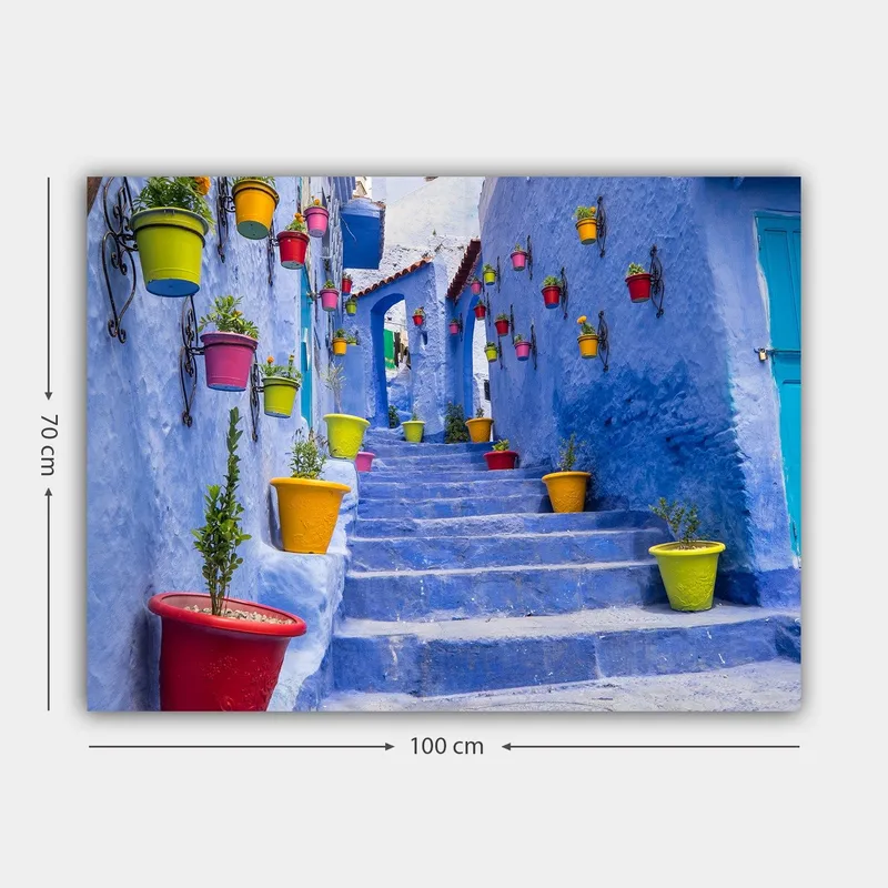 Lærred 70x100 cm - Farverig trappe omgivet af blomsterkrukker i et malerisk, blåt bymiljø - Blå / Gul / Rød - Boligtilbehør - Billeder & kunst - Billeder på lærred
