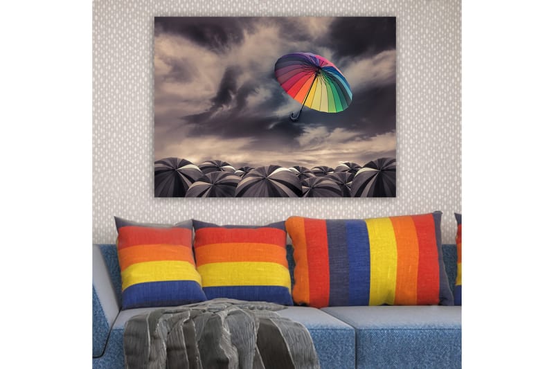Lærred 70x100 cm - Farverig paraply svæver over en samling grå paraplyer under en dramatisk overskyet himmel - Regnbuefarver / Grå - Boligtilbehør - Billeder & kunst - Billeder på lærred