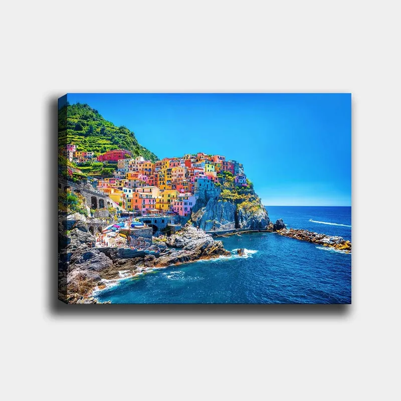 Lærred 70x100 cm - Farverige huse, der klatrer op ad en klippe ved havet, Blå / Gul / Lyserød