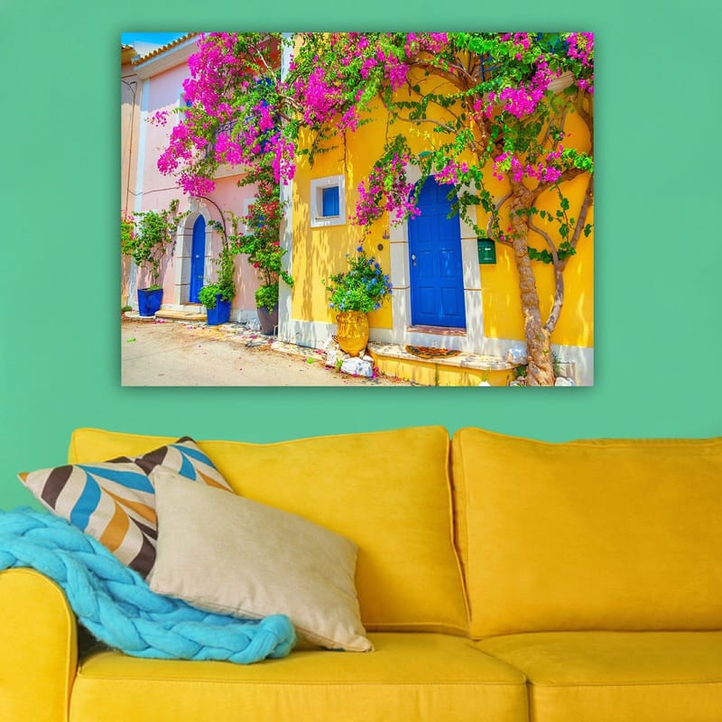 Lærred 70x100 cm - Farverige huse med bougainvillea i blomst på en travl gade - Blå / Gul / Lyserød - Boligtilbehør - Billeder & kunst - Billeder på lærred