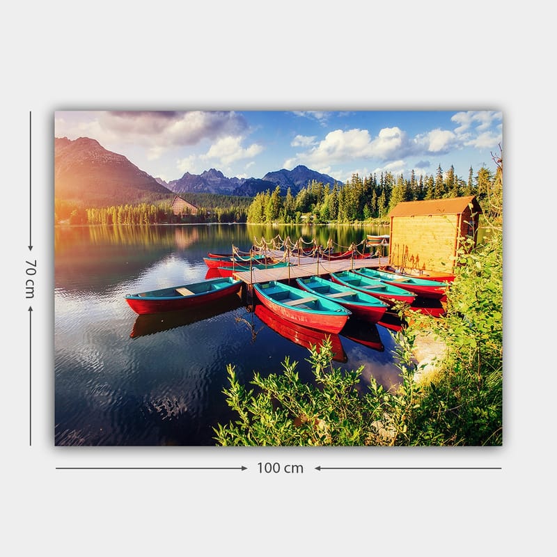 Lærred 70x100 cm - Flere farverige både ligger på en spejlblank sø omgivet af frodige træer og bjerge - Rød / Turkis / Grøn - Boligtilbehør - Billeder & kunst - Billeder på lærred