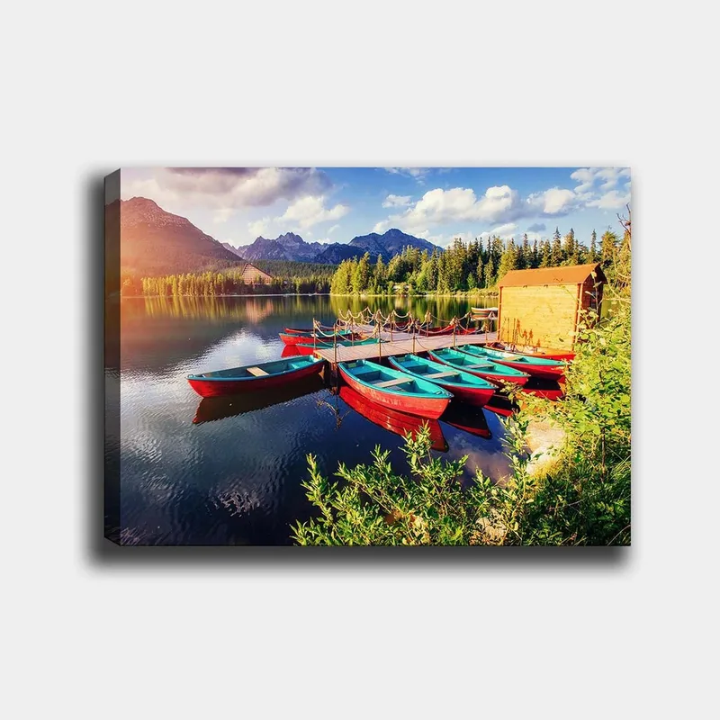 Lærred 70x100 cm - Flere farverige både ligger på en spejlblank sø omgivet af frodige træer og bjerge, Rød / Turkis / Grøn