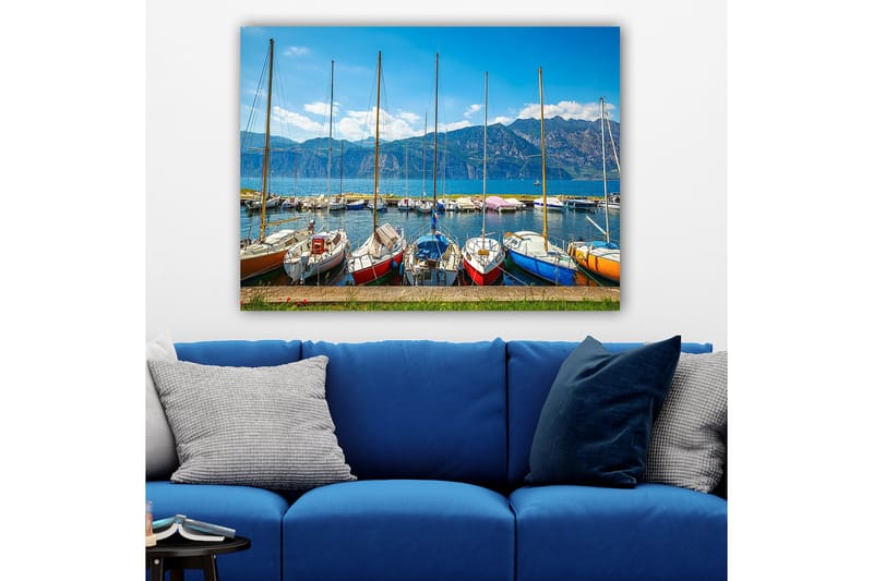Lærred 70x100 cm - Flere farverige sejlbåde i en havn med bjerge i baggrunden, Blå / Rød / Orange
