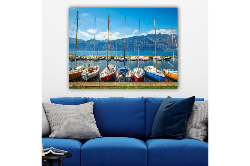 Lærred 70x100 cm - Flere farverige sejlbåde i en havn med bjerge i baggrunden, Blå / Rød / Orange