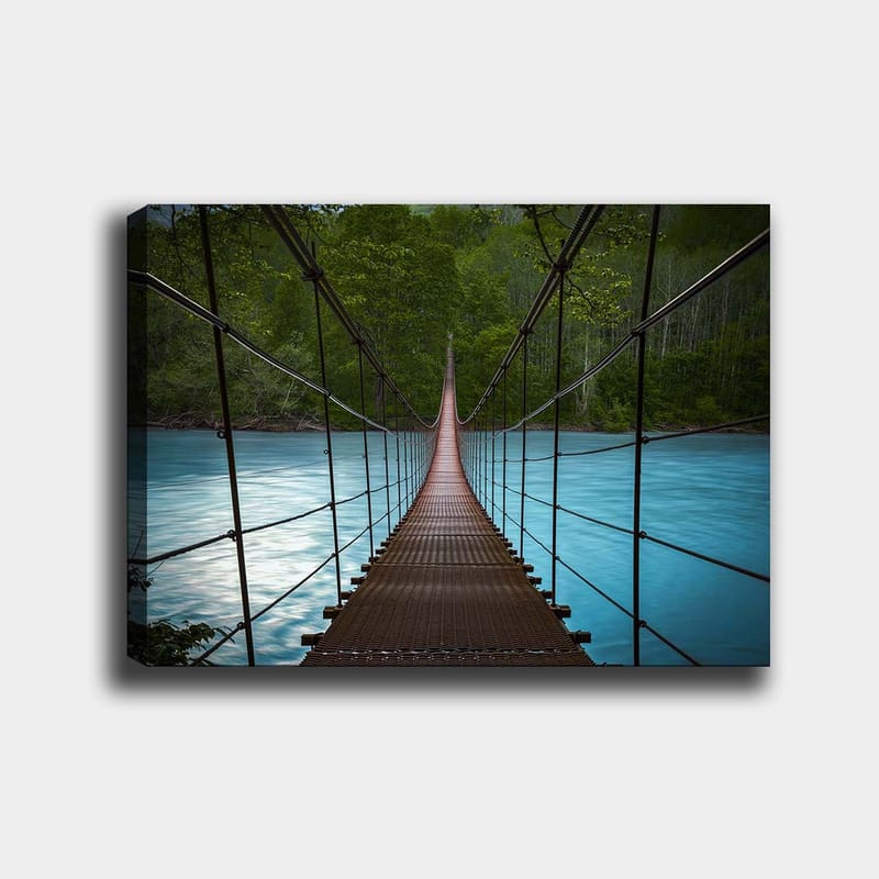 Lærred 70x100 cm - Hængebro over en rolig, blå flod omgivet af frodige træer, Mørkebrun / Turkis / Grøn