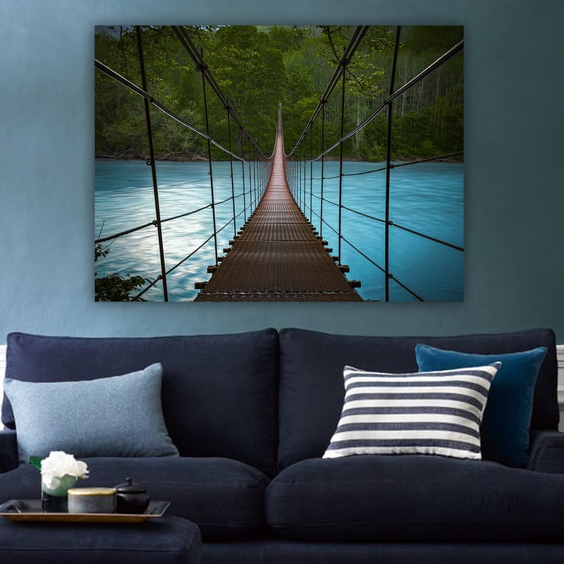 Lærred 70x100 cm - Hængebro over en rolig, blå flod omgivet af frodige træer - Mørkebrun / Turkis / Grøn - Boligtilbehør - Billeder & kunst - Billeder på lærred