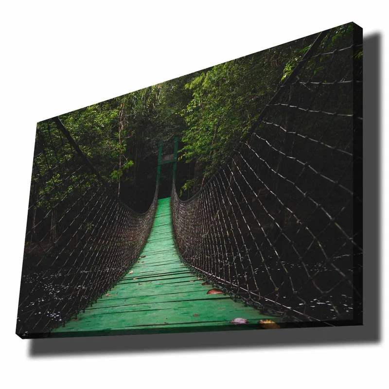 Lærred 70x100 cm - Hængebro strækker sig gennem en frodig skov, Grøn / Sort