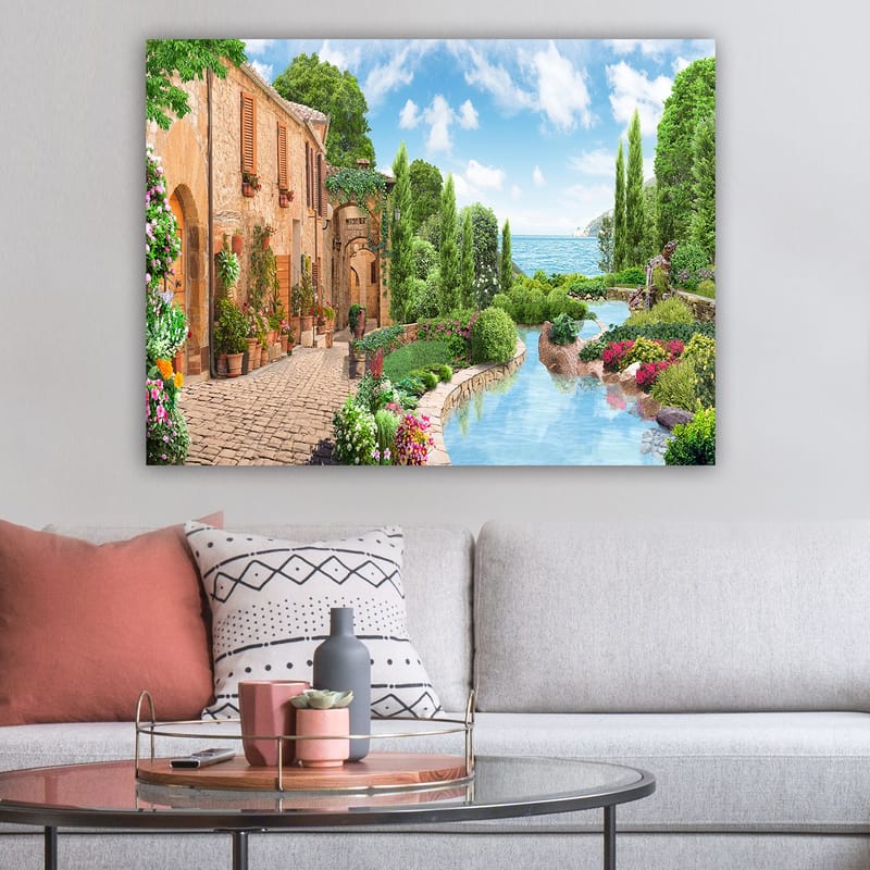 Lærred 70x100 cm - Idyllisk landsby med blomster, træer og en glitrende sø i baggrunden - Grøn / Blå / Terrakotta - Boligtilbehør - Billeder & kunst - Billeder på lærred