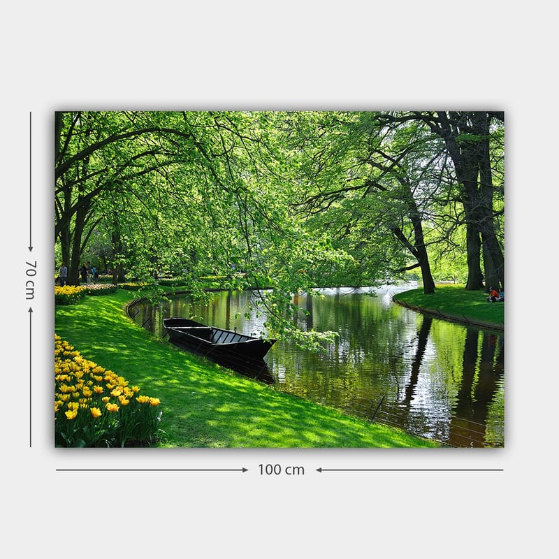 Lærred 70x100 cm - Idyllisk søscene med en båd, der ligger stille på en grøn bred omgivet af træer og blomster - Grøn / Sort / Gul - Boligtilbehør - Billeder & kunst - Billeder på lærred