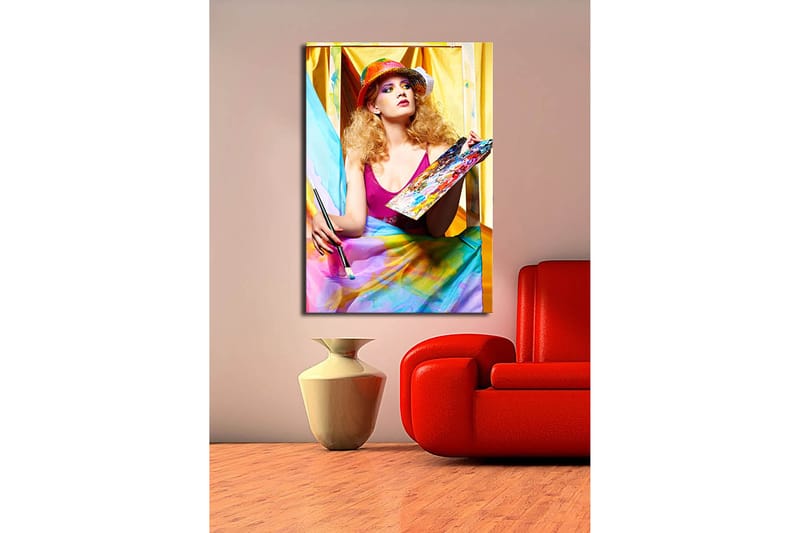 Lærred 70x100 cm - Kreativ kvinde der maler med en palet i hånden, omgivet af farverige stoffer - Lyserød / Blå / Gul - Boligtilbehør - Billeder & kunst - Billeder på lærred