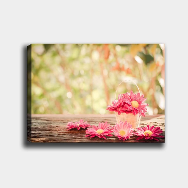 Lærred 70x100 cm - Kurv fyldt med lyserøde blomster på en træoverflade, Lyserød / Gul / Brun
