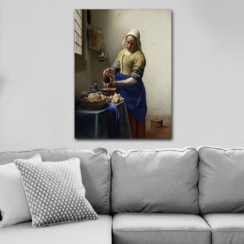 Lærred 70x100 cm - Kvinde hælder mælk i en skål i et lyst køkken - Blå / Gul / Brun - Boligtilbehør - Billeder & kunst - Billeder på lærred
