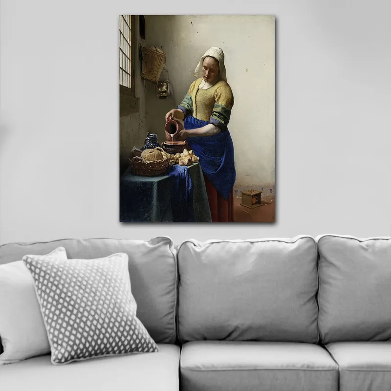 Lærred 70x100 cm - Kvinde hælder mælk i en skål i et lyst køkken - Blå / Gul / Brun - Boligtilbehør - Billeder & kunst - Billeder på lærred