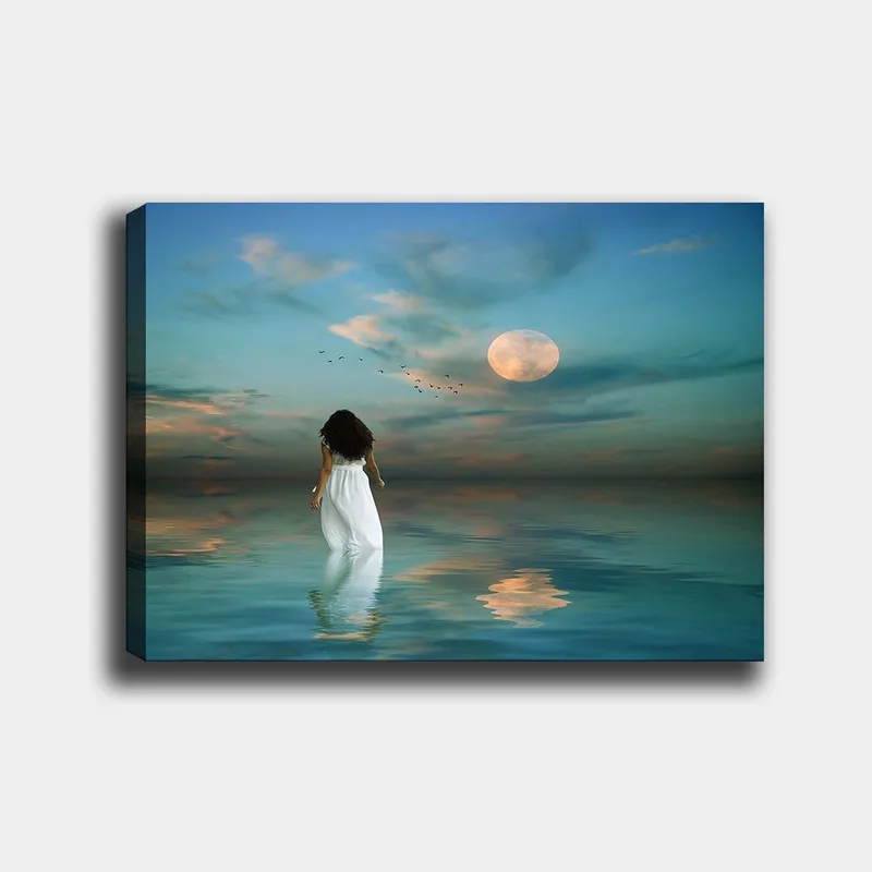Lærred 70x100 cm - Kvinde i hvid kjole går gennem et spejlblankt hav under en stjerneklar himmel med en stor måne, Blå / Hvid / Grå