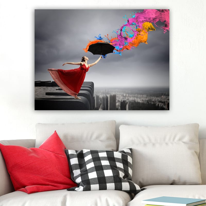 Lærred 70x100 cm - Kvinde i rød kjole står på en kant og holder en paraply, mens farverige malingsstråler sprøjter ud fra den - Rød / Sort / Orange - Boligtilbehør - Billeder & kunst - Billeder på lærred