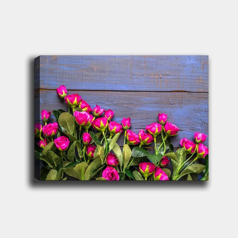 Lærred 70x100 cm - Livlig samling af lyserøde roser mod en blå træbaggrund, Lyserød / Grøn / Blå