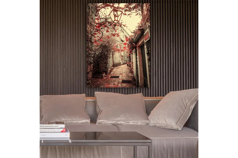 Lærred 70x100 cm - Malerisk gyde omkranset af gamle bygninger og blomster i røde nuancer, Rød / Beige