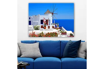 Lærred 70x100 cm - Malerisk udsigt over en hvidkalket bygning med en traditionel vindmølle og farverige blomster på Santorini - Hvid / Blå / Rød - Boligtilbehør - Billeder & kunst - Billeder på lærred