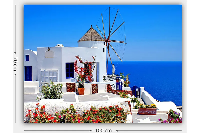 Lærred 70x100 cm - Malerisk udsigt over en hvidkalket bygning med en traditionel vindmølle og farverige blomster på Santorini - Hvid / Blå / Rød - Boligtilbehør - Billeder & kunst - Billeder på lærred