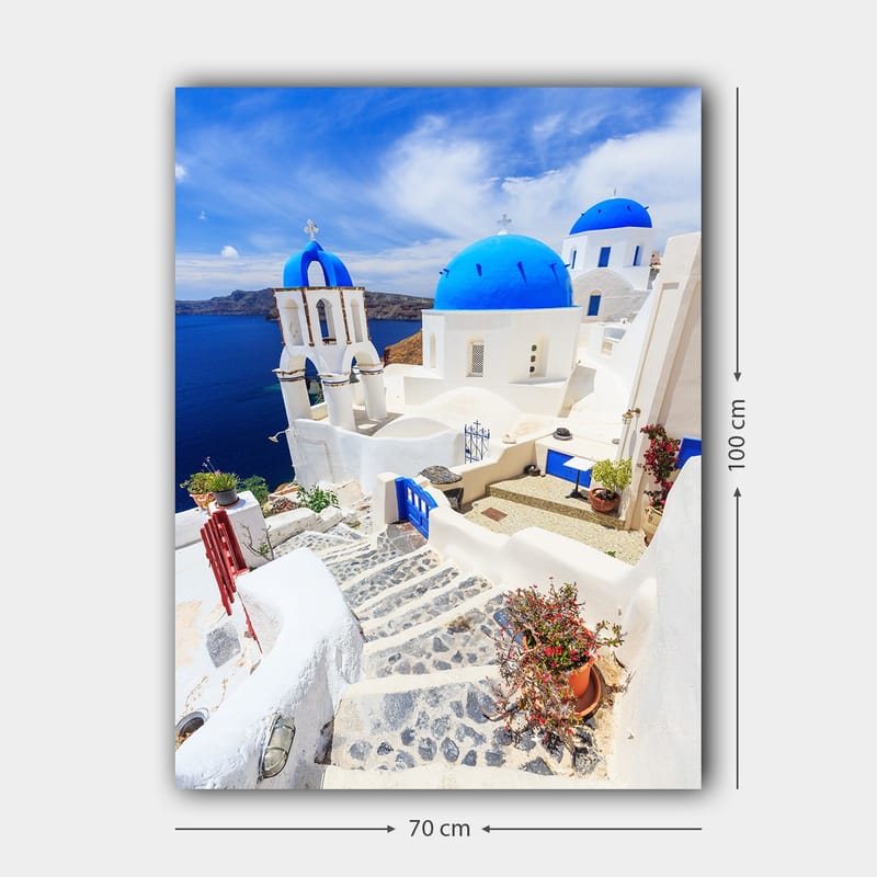 Lærred 70x100 cm - Malerisk udsigt over hvide huse med blå kupler og en asfalteret vej i en græsk ø-omgivelse - Blå / Hvid - Boligtilbehør - Billeder & kunst - Billeder på lærred