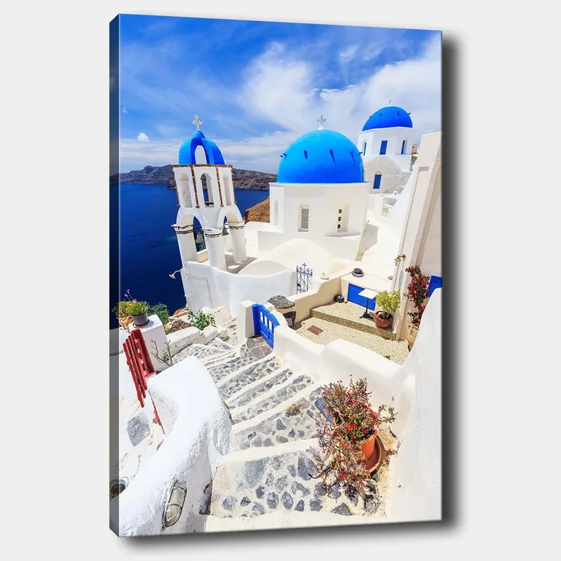 Lærred 70x100 cm - Malerisk udsigt over hvide huse med blå kupler og en asfalteret vej i en græsk ø-omgivelse, Blå / Hvid