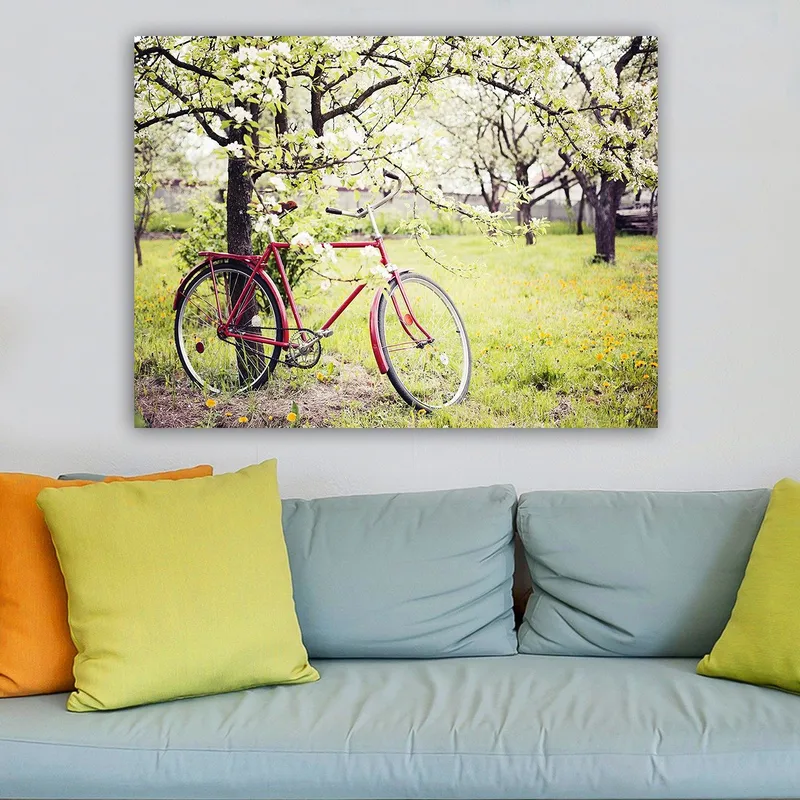 Lærred 70x100 cm - Rød cykel stående under blomstrende træer i et frodigt miljø, Rød / Grøn / Hvid