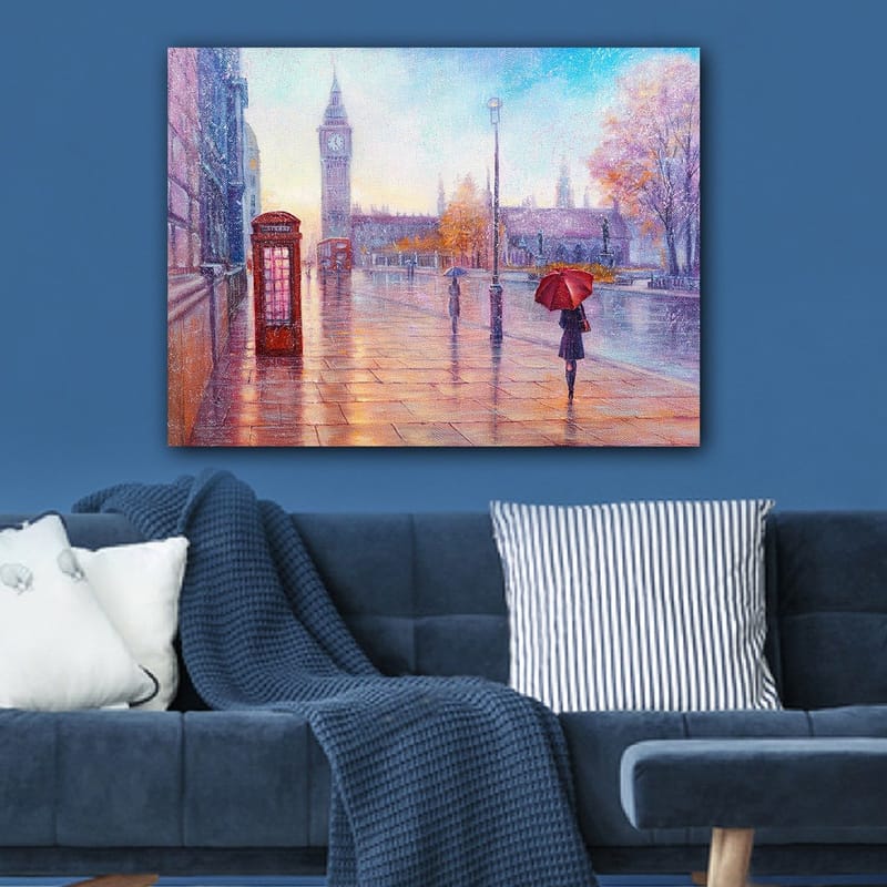 Lærred 70x100 cm - Regnfuldt bybillede med en rød telefonboks og en person med en rød paraply, der går langs en våd gade - Rød / Blå / Orange - Boligtilbehør - Billeder & kunst - Billeder på lærred