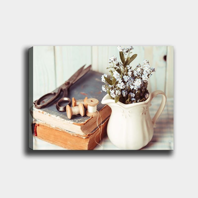 Lærred 70x100 cm - Rolig komposition af en kande med blomster, en bog og syredskaber, Lyseblå / Beige / Grøn