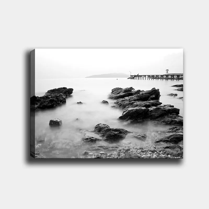 Lærred 70x100 cm - Roligt kystlandskab med klipper og en mole i det fjerne, Sort / Hvid / Grå