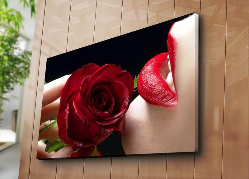 Lærred 70x100 cm - Sensuel nærbillede af en rose holdt tæt på en læbe med rød læbestift - Rød / Grøn - Boligtilbehør - Billeder & kunst - Billeder på lærred
