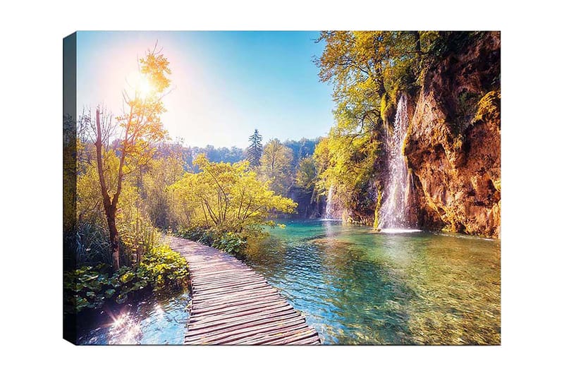 Lærred 70x100 cm - Smuk naturudsigt med en træbro, der fører gennem frodigt grønt og et vandfald i baggrunden, Grøn / Blå / Gul