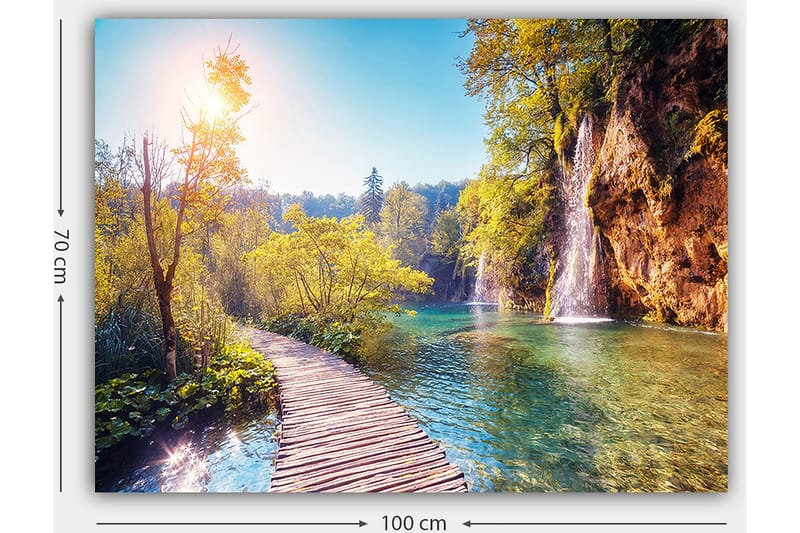 Lærred 70x100 cm - Smuk naturudsigt med en træbro, der fører gennem frodigt grønt og et vandfald i baggrunden - Grøn / Blå / Gul - Boligtilbehør - Billeder & kunst - Billeder på lærred