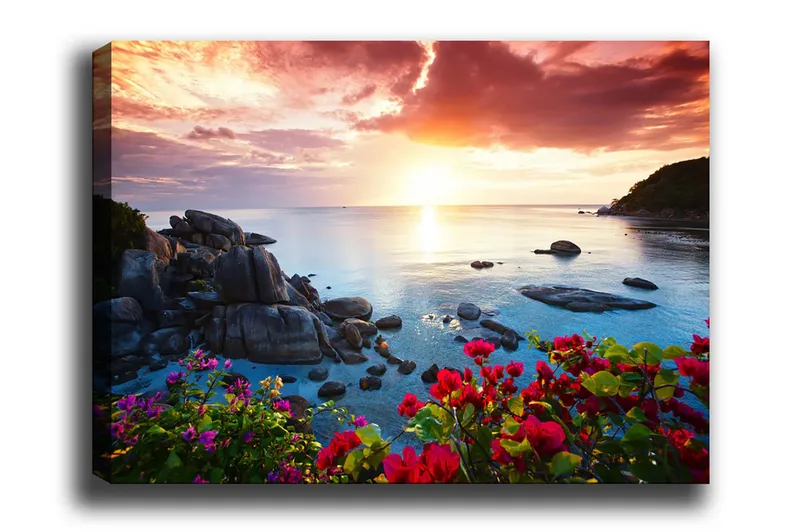 Lærred 70x100 cm - Smuk solnedgang over havet med klipper og farverige blomster i forgrunden, Lyserød / Blå / Orange