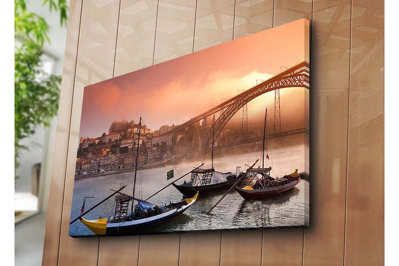 Lærred 70x100 cm - Smuk udsigt over floden med traditionelle både og en majestætisk bro i baggrunden, omgivet af farverige huse - Orange / Blå / Gul - Boligtilbehør - Billeder & kunst - Billeder på lærred