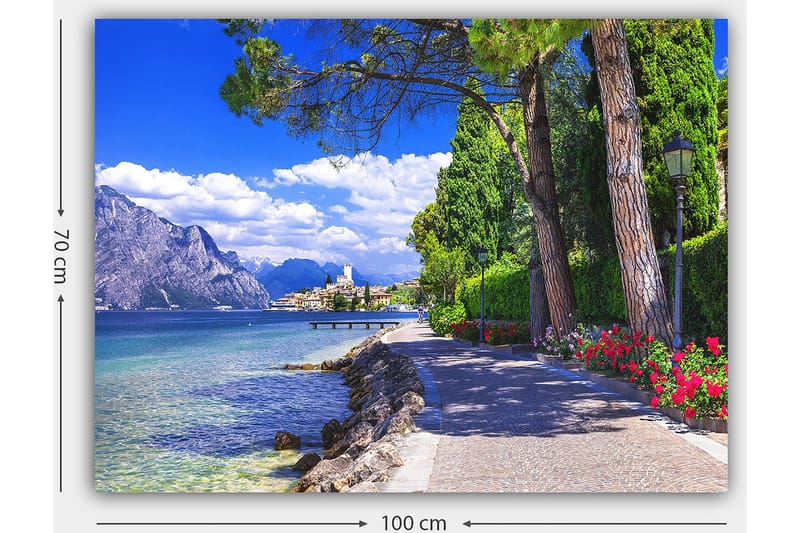 Lærred 70x100 cm - Smuk promenade med træer og blomster ved en sø, omgivet af bjerge og en malerisk by i baggrunden - Blå / Grøn / Rød - Boligtilbehør - Billeder & kunst - Billeder på lærred