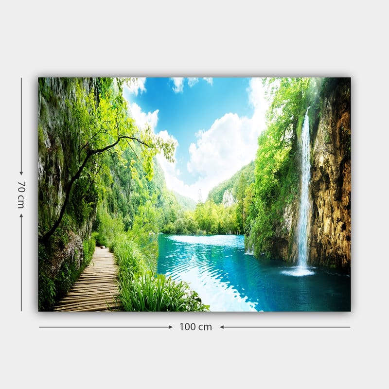 Lærred 70x100 cm - Smukt natursceneri med et vandfald, der løber ud i en klar, blå sø omgivet af frodigt grønt og bjerge - Grøn / Blå - Boligtilbehør - Billeder & kunst - Billeder på lærred