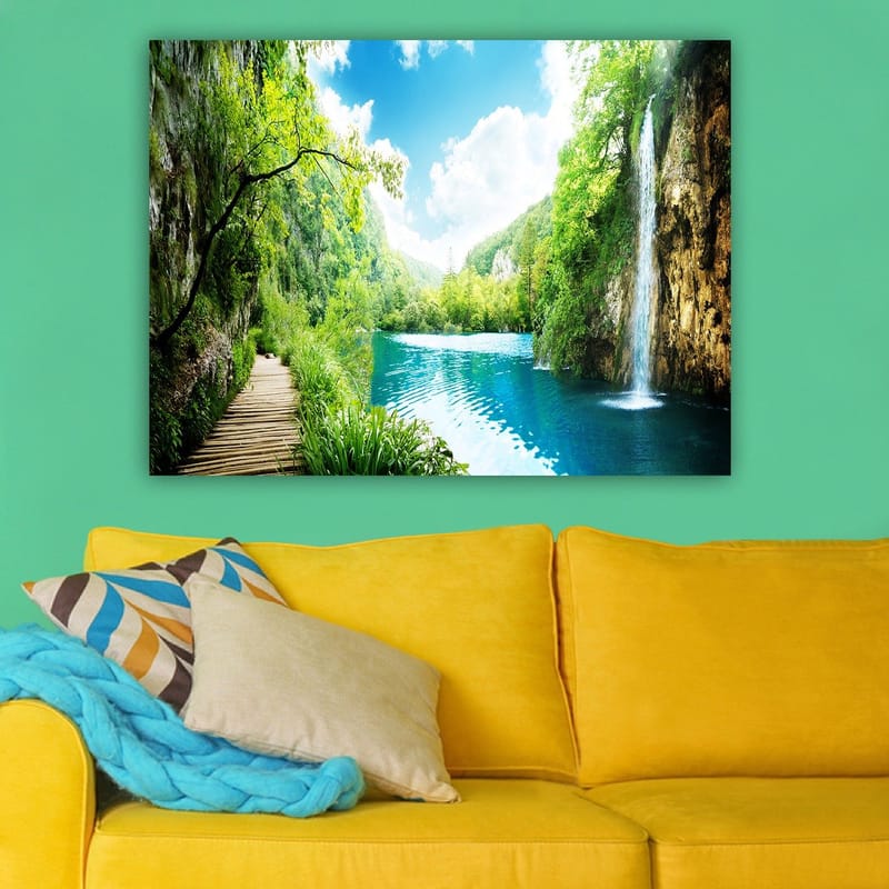 Lærred 70x100 cm - Smukt natursceneri med et vandfald, der løber ud i en klar, blå sø omgivet af frodigt grønt og bjerge - Grøn / Blå - Boligtilbehør - Billeder & kunst - Billeder på lærred