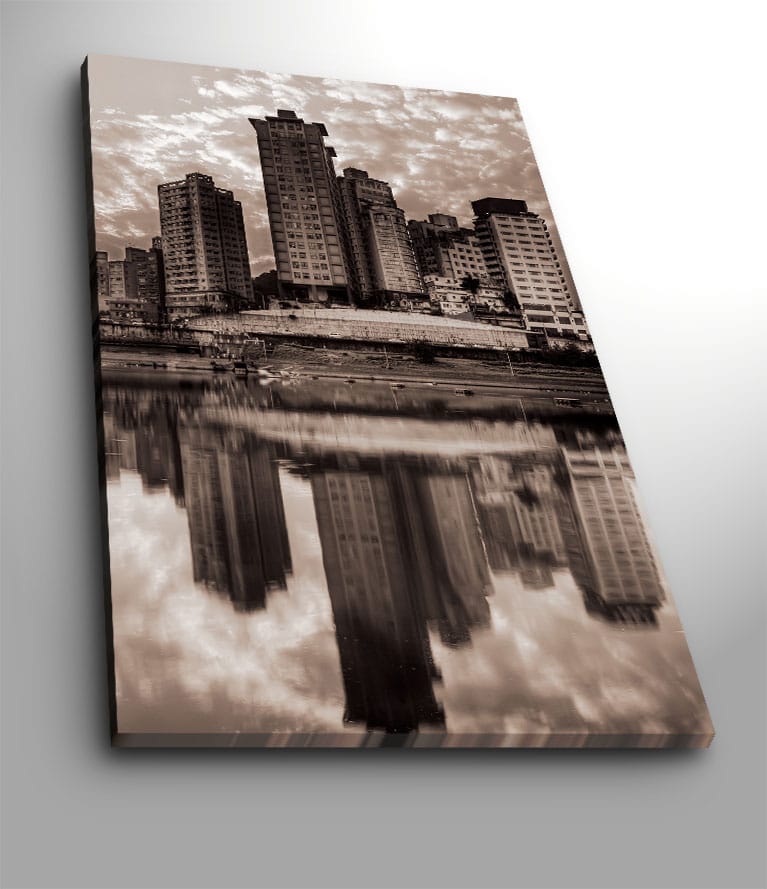 Lærred 70x100 cm - Sort-hvid bysilhuet med høje bygninger spejlet i vandet, Sort / Hvid / Grå