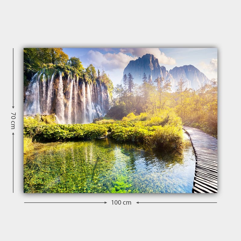 Lærred 70x100 cm - Storslået vandfald omgivet af frodig vegetation og majestætiske bjerge - Grøn / Blå / Gul - Boligtilbehør - Billeder & kunst - Billeder på lærred